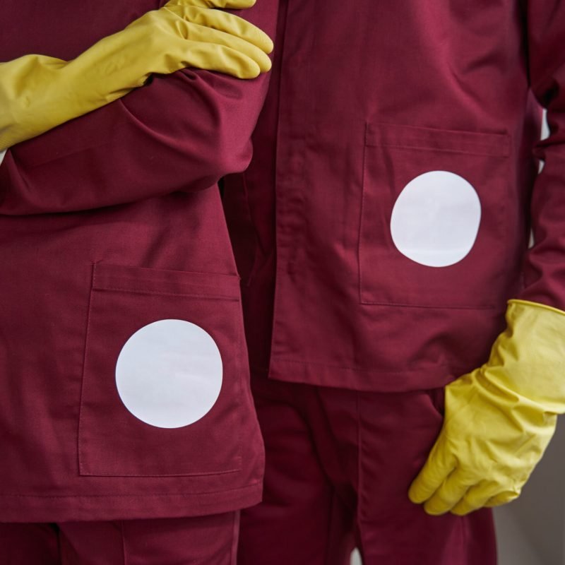 Cropped photo of two janitors wearing rubber gloves and uniforms in workplace