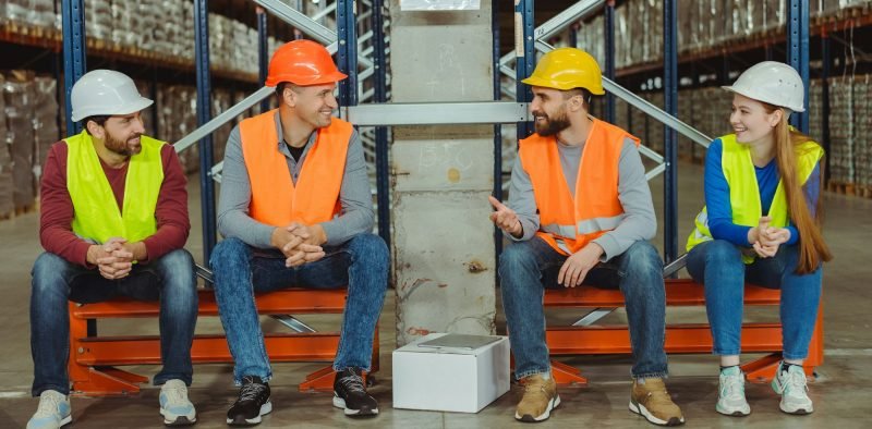 Successful, professional workers, engineers wearing hard hats and work wear talking, discussing